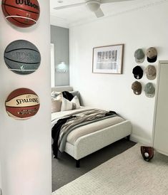 a bed room with a neatly made bed and basketballs on the wall above it