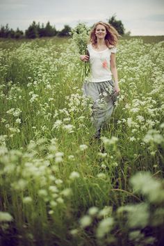 a woman is walking through the tall grass