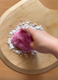 a person is peeling an apple into powdered sugar on a wooden cutting board with a knife