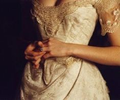 a woman in a white dress is holding her hands together