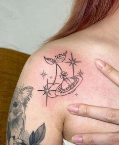 a woman's shoulder with tattoos on it and an image of a dog in space