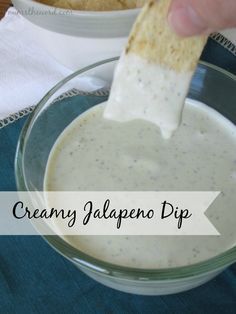 a person dipping some food into a glass bowl with a cracker in it and the words creamy jalapeno dip