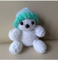 a crocheted white teddy bear with green hair