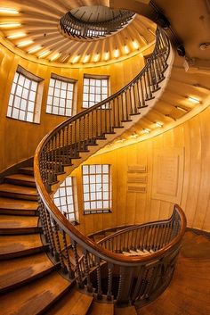 a spiral staircase in the middle of a building with windows on each side and wooden floors