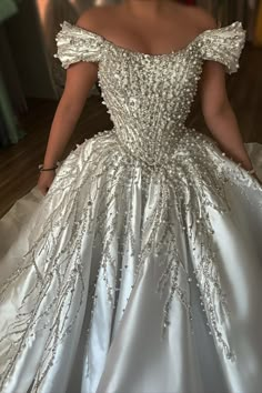 a woman in a white ball gown is looking down at her dress while standing on the floor