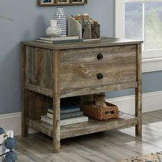 a wooden table with two drawers and a basket on it's shelf next to a window