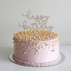 a pink birthday cake with gold sprinkles and a happy birthday topper