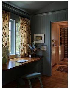 a home office with wooden floors and blue walls, along with curtains on the windows