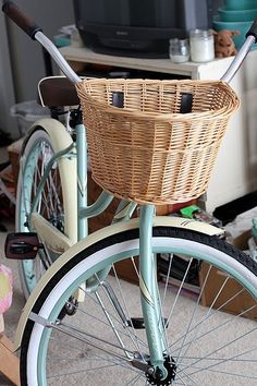 a basket on the back of a bicycle parked in front of a tv and other items