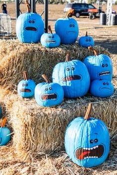 pumpkins with faces painted on them sitting in hay bales