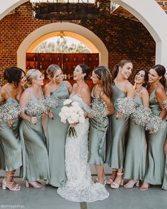 a group of women standing next to each other in front of a brick wall holding bouquets