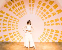 a woman standing in front of a wall with words on it