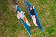 two people laying in hammocks on the grass with their feet propped against each other