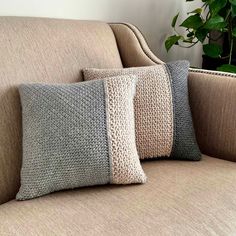 three pillows sitting on top of a couch next to a potted plant