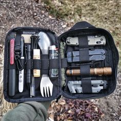 an open black case filled with lots of different tools and gadgets in the woods