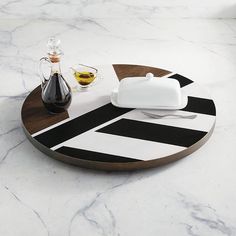 a wooden tray with black and white designs on it, next to a bottle of olive oil