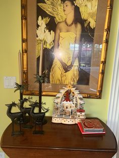 there is a painting on the wall above a table with two candles and other decorations