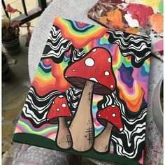 someone is holding up a colorful mushroom painting