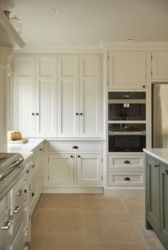 a large kitchen with white cabinets and marble counter tops