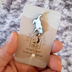 a person holding up a card with a cat on it's back and a keychain attached to it