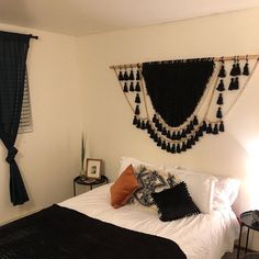 a black and white bedroom with tassels hanging on the wall above the bed