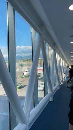 people are standing in an airport terminal looking out the windows at planes on the tarmac