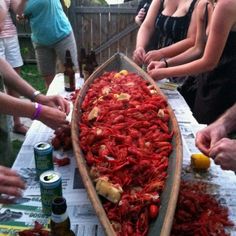 several people standing around a boat with craws on the table and beer bottles