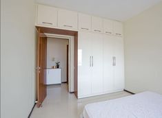 a bedroom with white cupboards and a bed