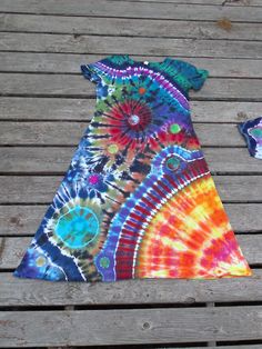 a tie - dyed dress sitting on top of a wooden deck