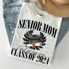 Senior Class Of 2024/Senior Mom Class Of 2024 Tee Graphic Design: The pattern of this t-shirt features a bold graphic design, making it stand out from other regular tees. Crew Neckline: The crew neckline adds a classic touch to the casual, fashion-forward style of this t-shirt. Casual Occasion: Perfect for casual occasions such as hanging out with friends or running errands, the Senior Class Of 2024/Senior Mom Class Of 2024 Tee is an essential addition to your wardrobe. Fits All Sizes: Available Black T-shirt With Graphic Print For Graduation, Black Graphic Print T-shirt For Graduation, Custom Print Cotton Tops For Graduation, Graduation T-shirt With Letter Print In Relaxed Fit, Graphic Tee Tops With Graphic Print For Graduation, Graphic Tee For Graduation, Tee Graphic Design, Plainfield Illinois, Senior Class Of 2024