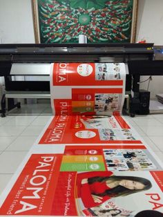 a large roll of red paper sitting on top of a white floor next to a printer