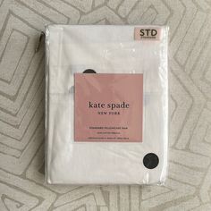 a white sheet with black dots on it and a pink label that says kate spade new york