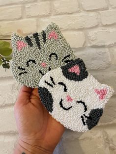 two handmade cat coasters sitting next to each other on top of a brick wall