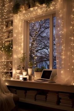 a laptop computer sitting on top of a desk next to a window covered in fairy lights