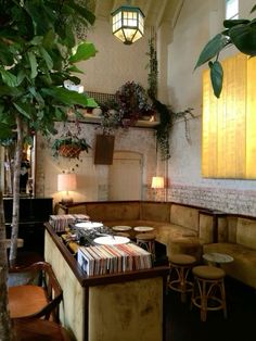 a room filled with lots of furniture next to a tree and potted plants on the wall