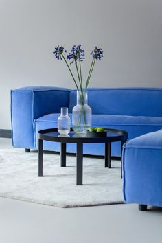 a blue couch and table with vases on it