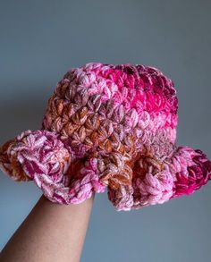 a woman's hand is holding a crocheted hat