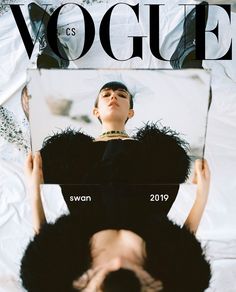 a magazine cover with a woman laying on top of a bed and another person standing in the background