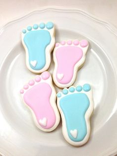 three decorated cookies sitting on top of a white plate with pink and blue feet in the middle