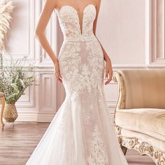 a woman in a white wedding dress standing next to a couch with flowers on it