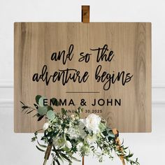 a wooden sign that says welcome to the bride and groom with flowers in front of it