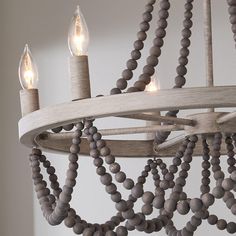 a chandelier with wooden beads hanging from it's sides and two candles in the middle