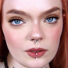 a woman with red hair and piercings on her nose