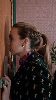 a woman is looking at the door handle on a wooden paneled room with pink wallpaper