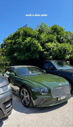 two cars parked next to each other in a parking lot with trees and bushes behind them