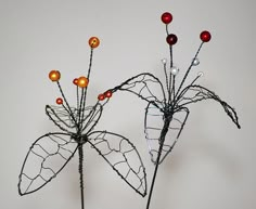 two wire flowers with red and yellow lights on them sitting in a vase next to each other