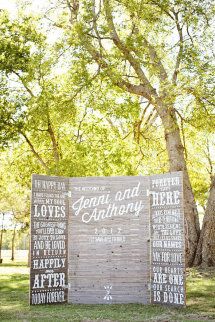 a wooden sign sitting in the grass next to trees