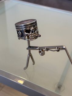 a glass topped table with a metal skeleton on it's legs holding a jar