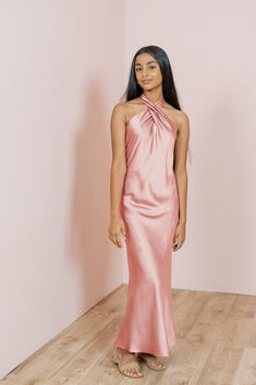 a woman standing in a room wearing a blue dress with an asymmetrical neckline