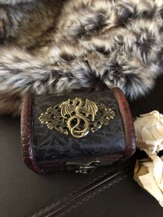 a black purse sitting on top of a table next to some white flowers and fur